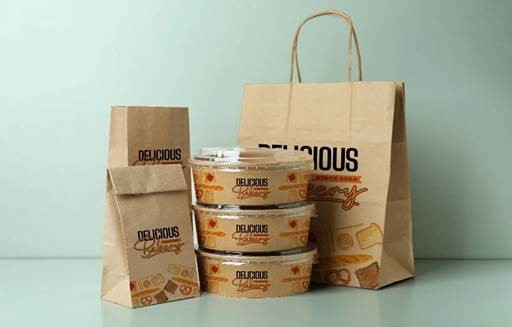 Eco-friendly bakery packaging set featuring kraft paper shopping bag, take-away bags, and printed food containers with bakery branding